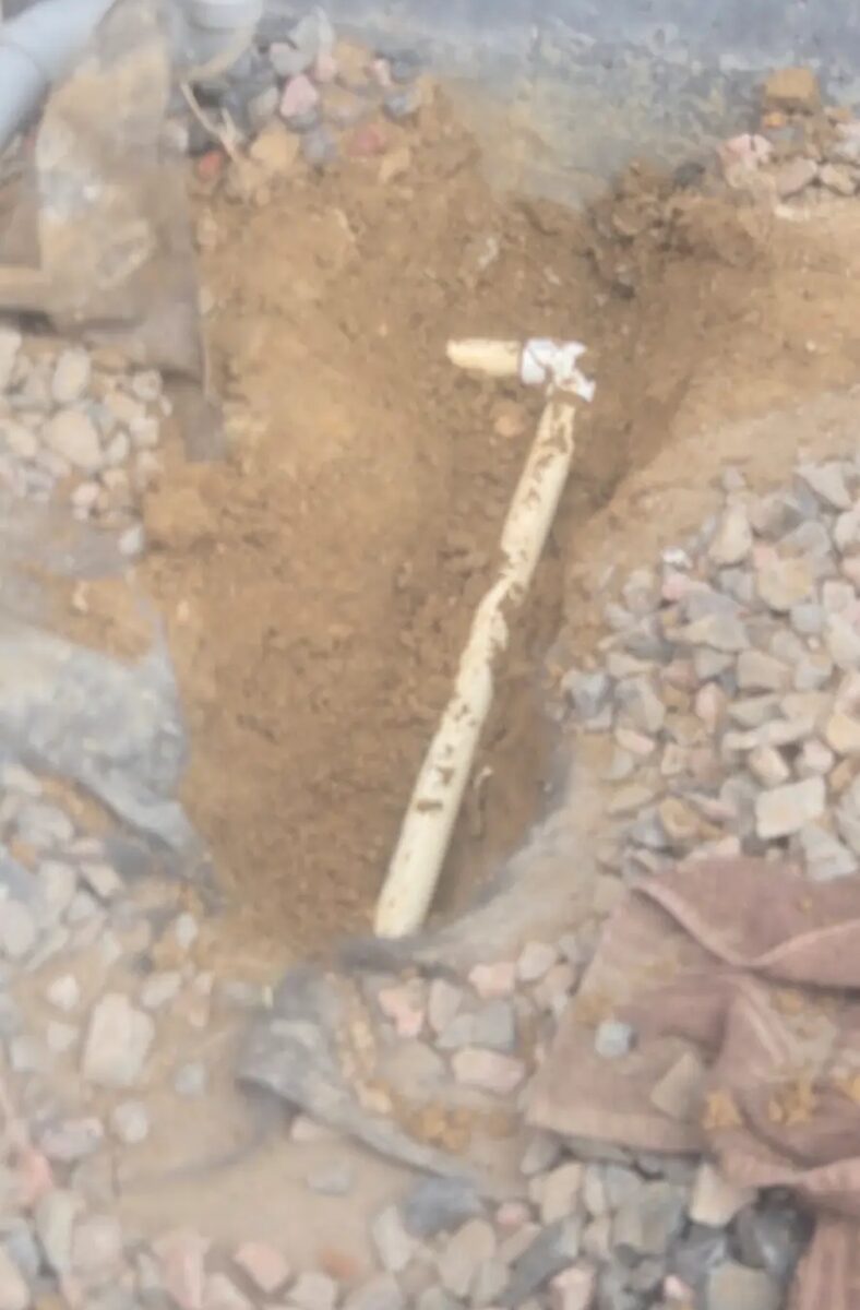 Broken lateral line exposed in rock and clay, cut back clean before a new fitting goes in.