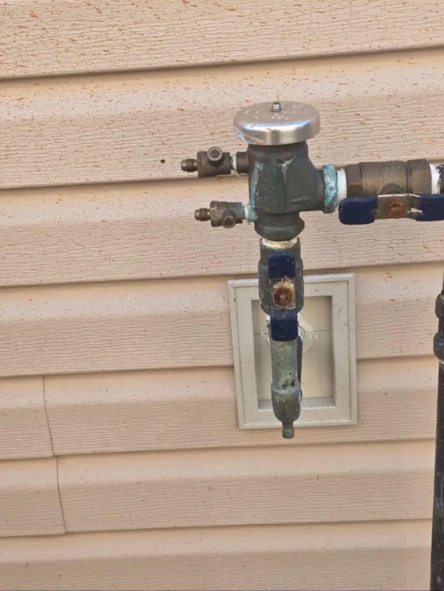 Exterior pressure vacuum breaker installed to code, protecting the home's drinking water supply.