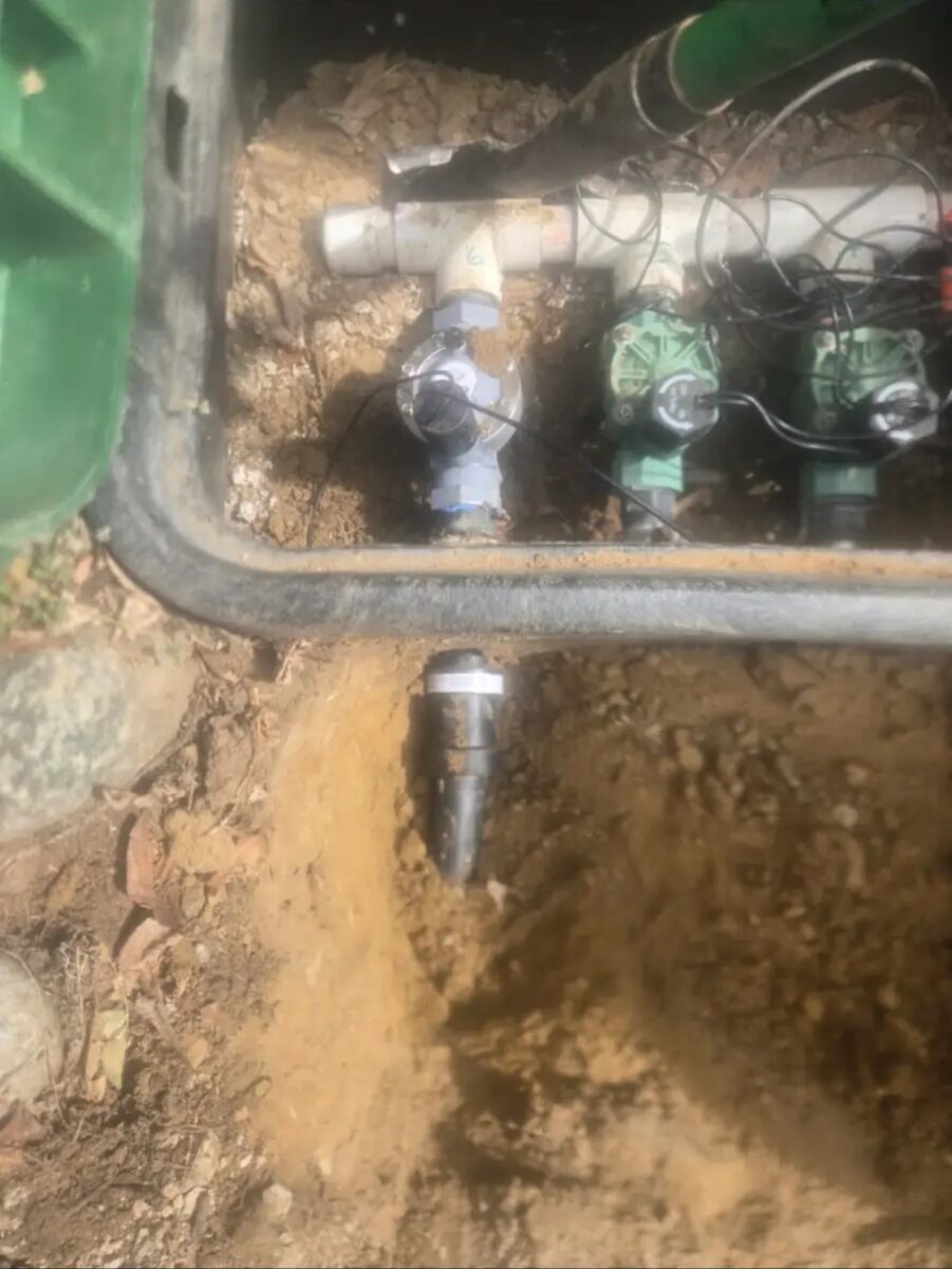 Manifold and new zone line staged in the trench before backfill.