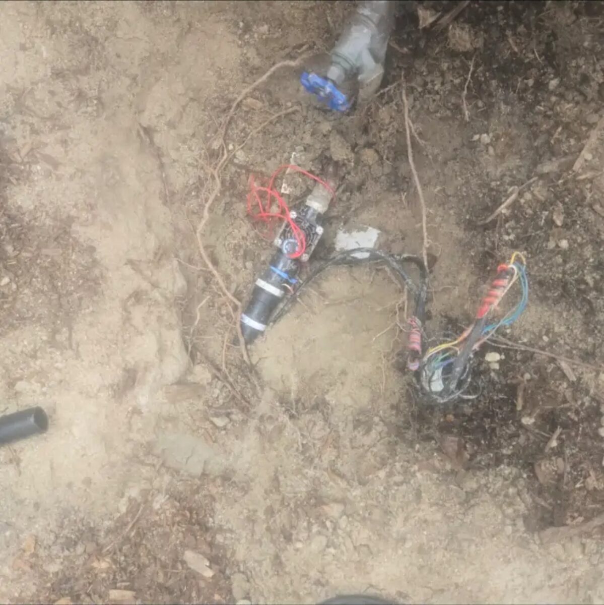 Valve and wire splice exposed in the trench during a zone-down diagnosis.